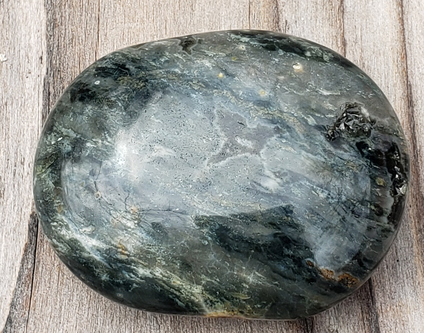 A polished Ocean Jasper palm stone with visible green color and natural patterns, containing a druzy vug. PS08-5