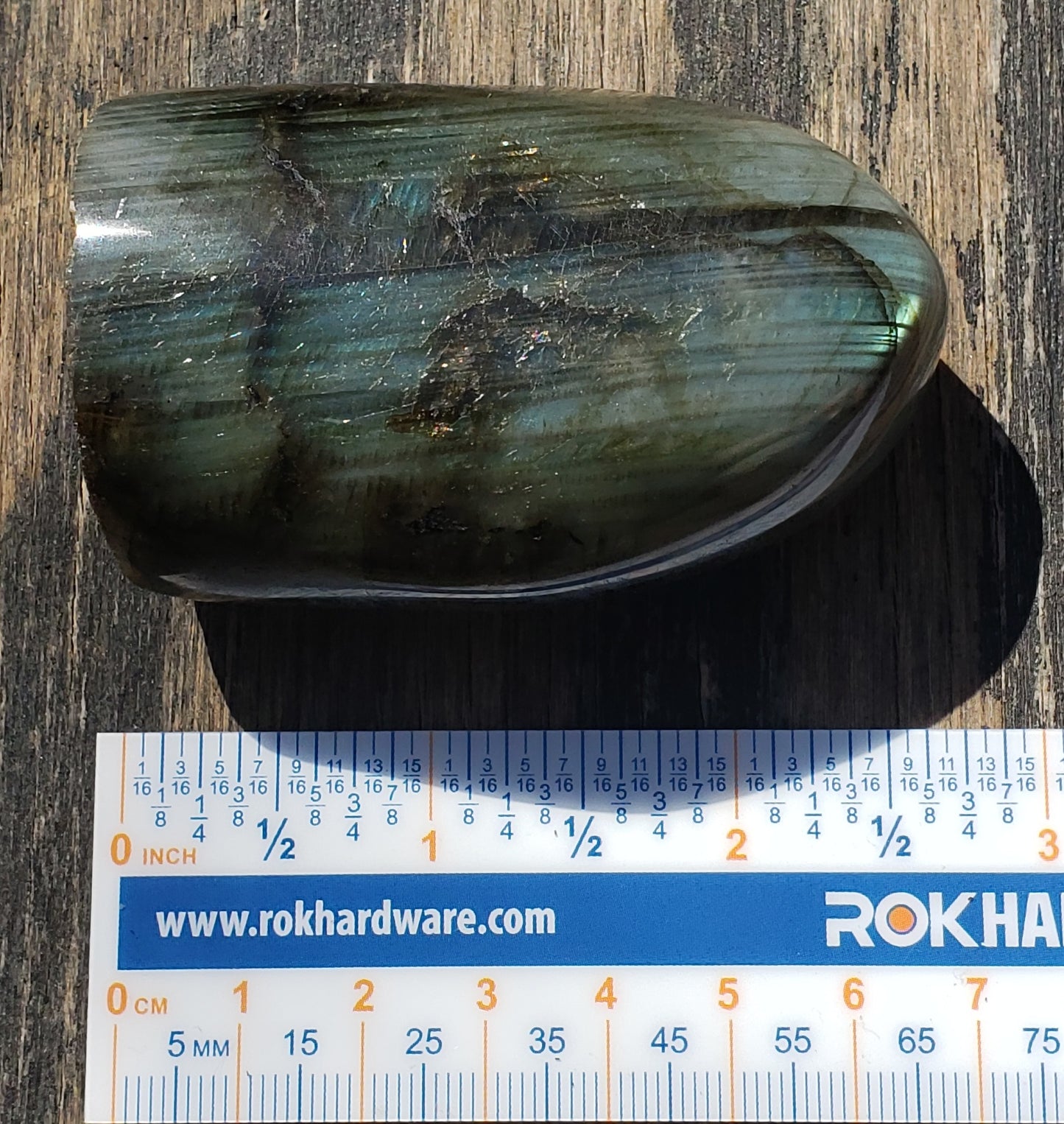 Polished labradorite freeform crystal showing vibrant blue and teal flash with natural striated patterning ruler FF04-3
