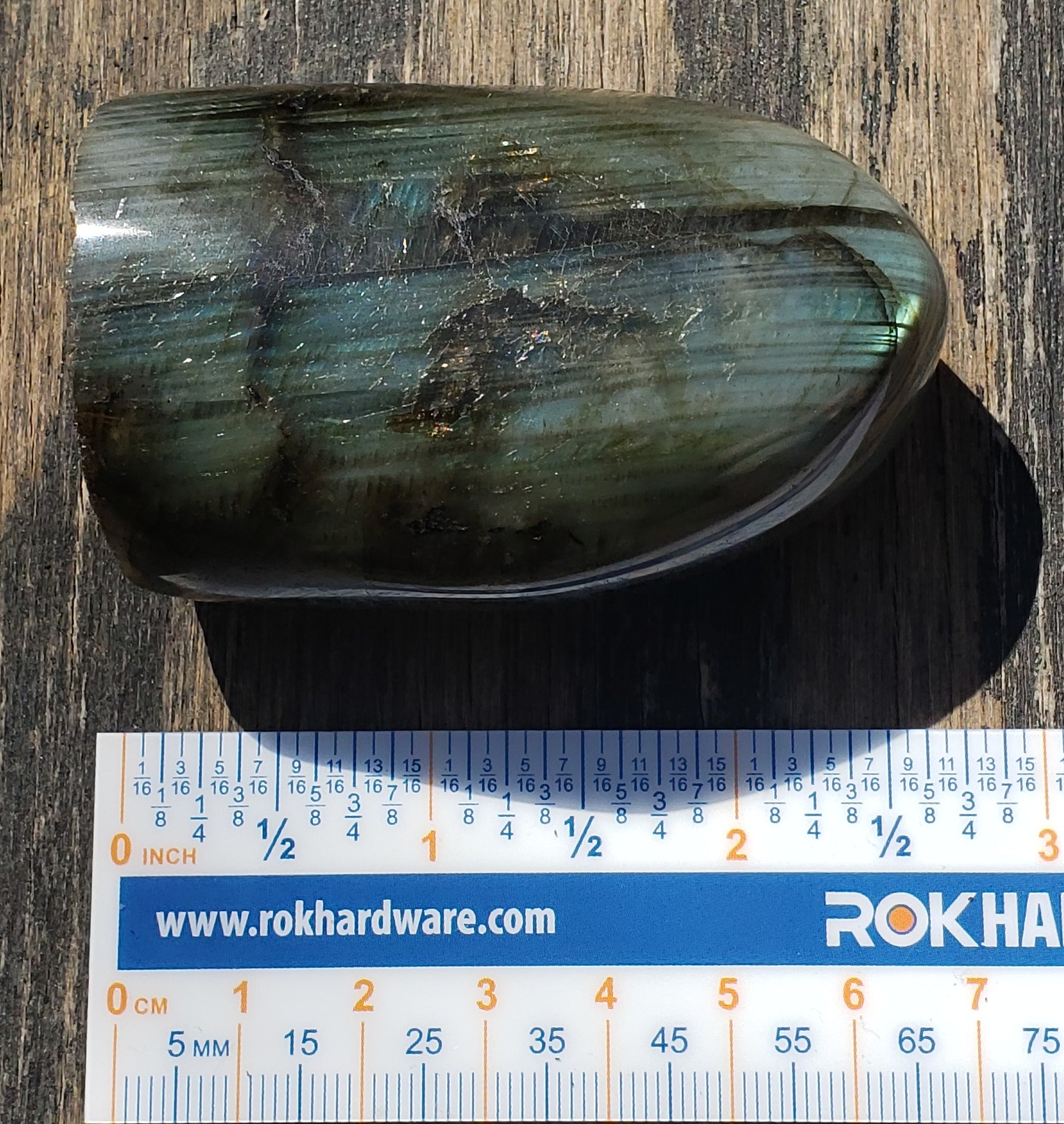 Polished labradorite freeform crystal showing vibrant blue and teal flash with natural striated patterning ruler FF04-3
