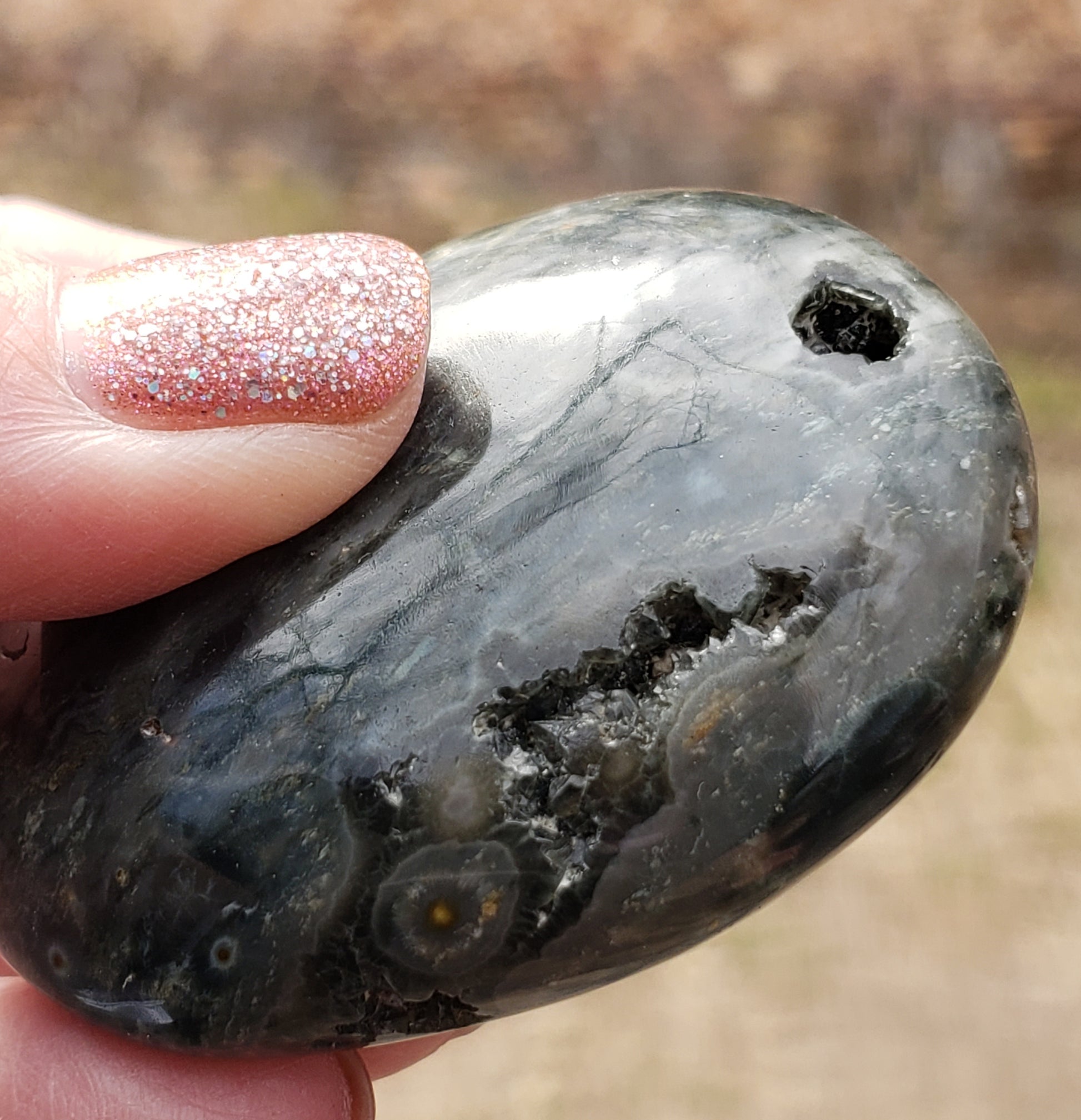 A polished Ocean Jasper palm stone with visible green color and natural patterns, containing a druzy vug. PS08-4