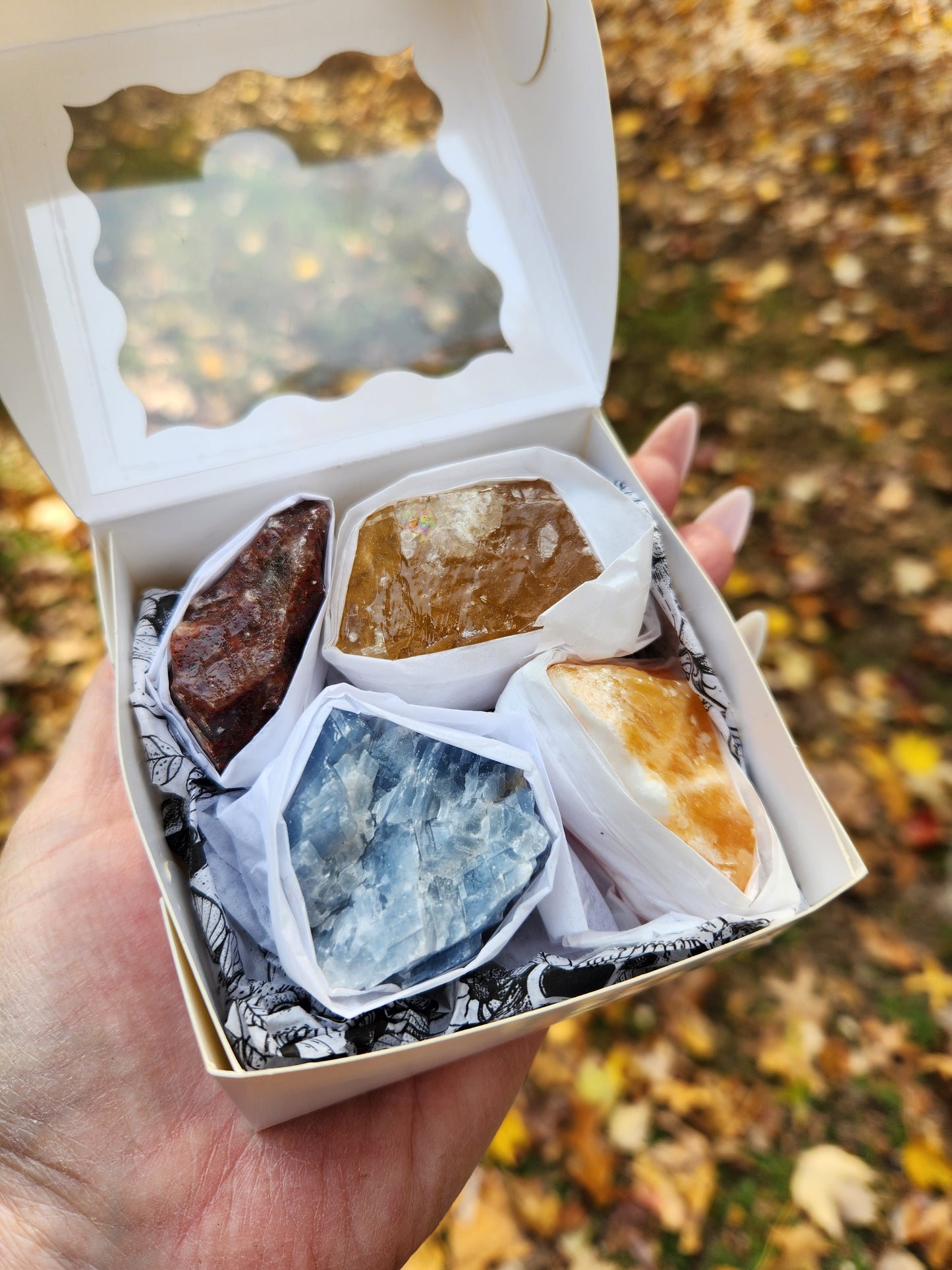 Colorful rough calcite pieces packaged as a crystal gift in hand for size