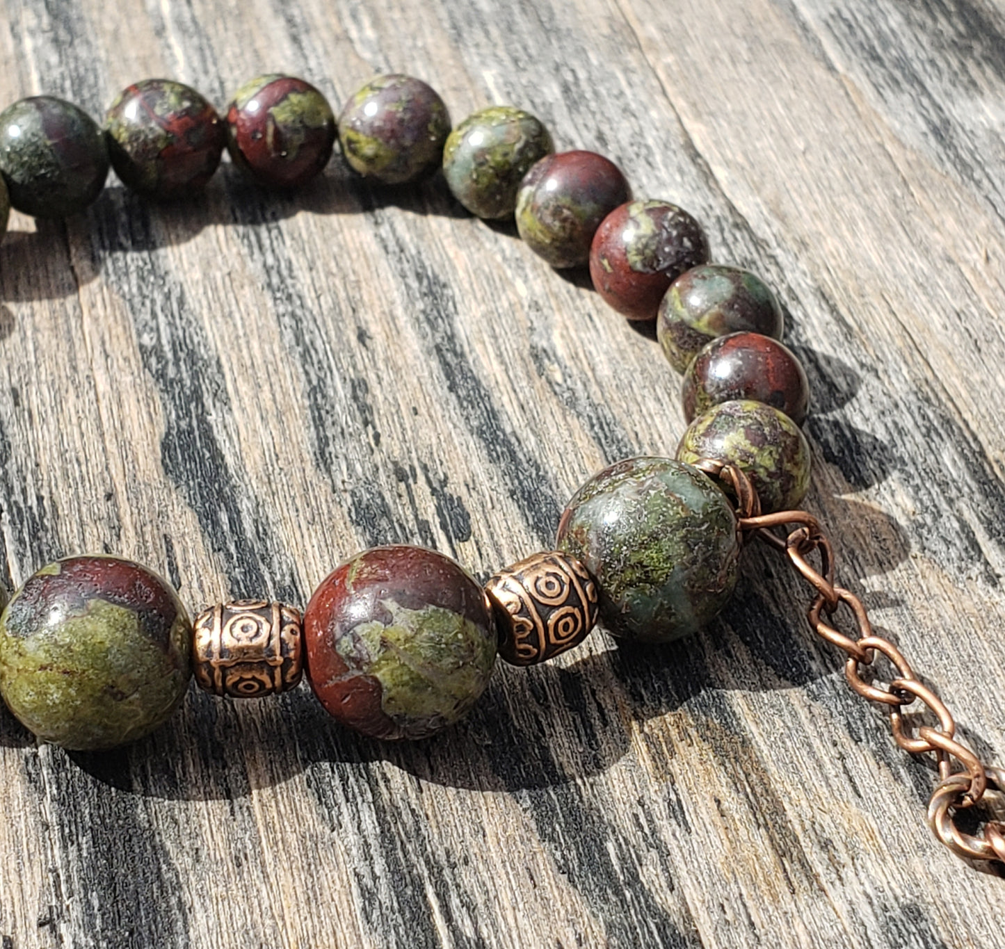 Dragon’s Blood Jasper stretch bracelet with crystal blood-drop dangle charm close up of beads